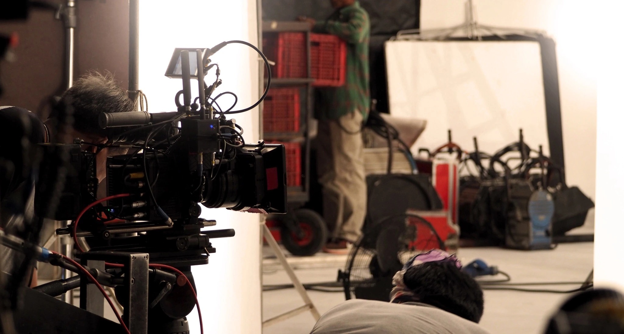 Camera operator working with a professional video camera and studio equipment.