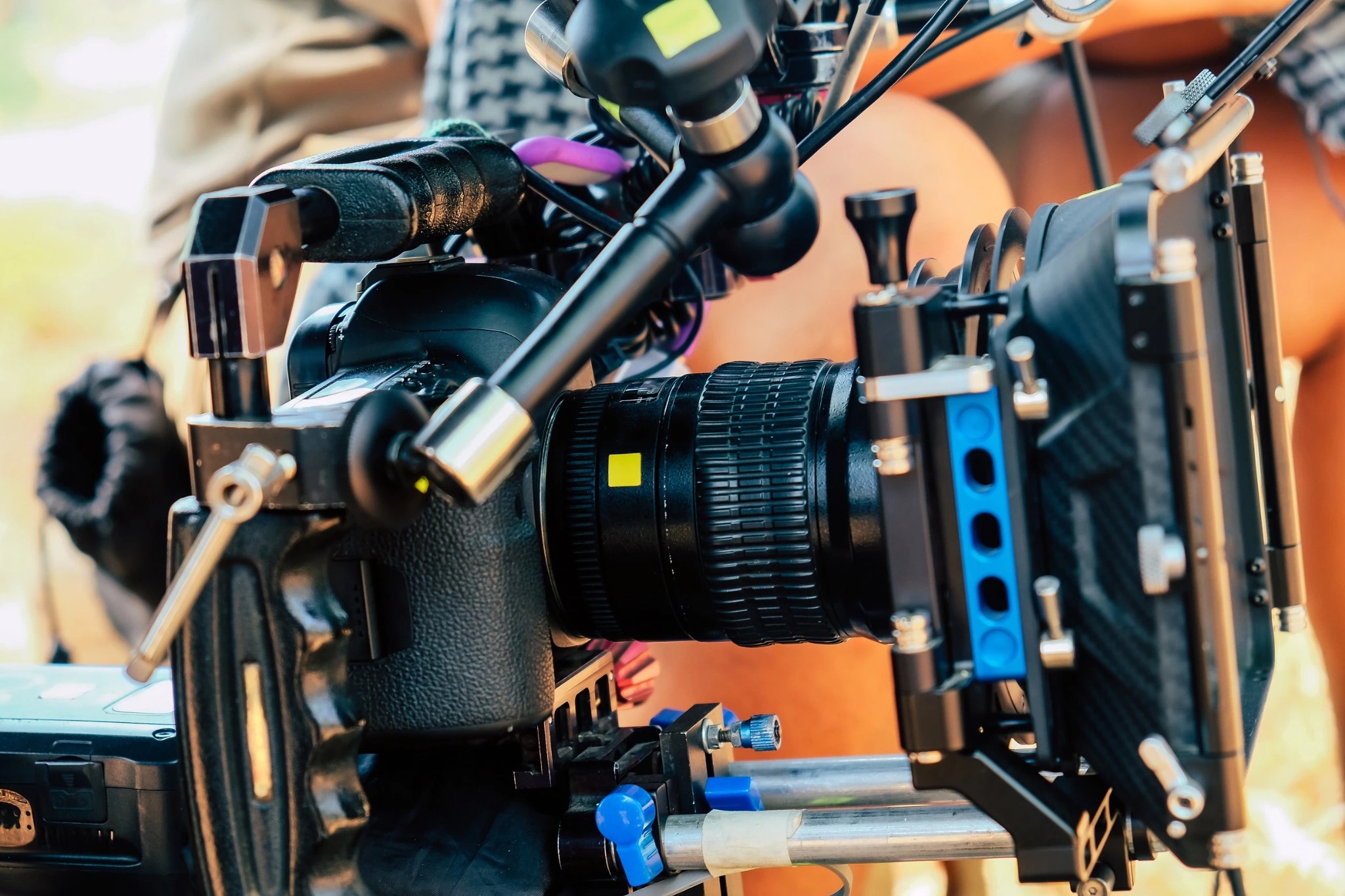 Close-up of a cinema camera with a lens, support rails and matte box.
