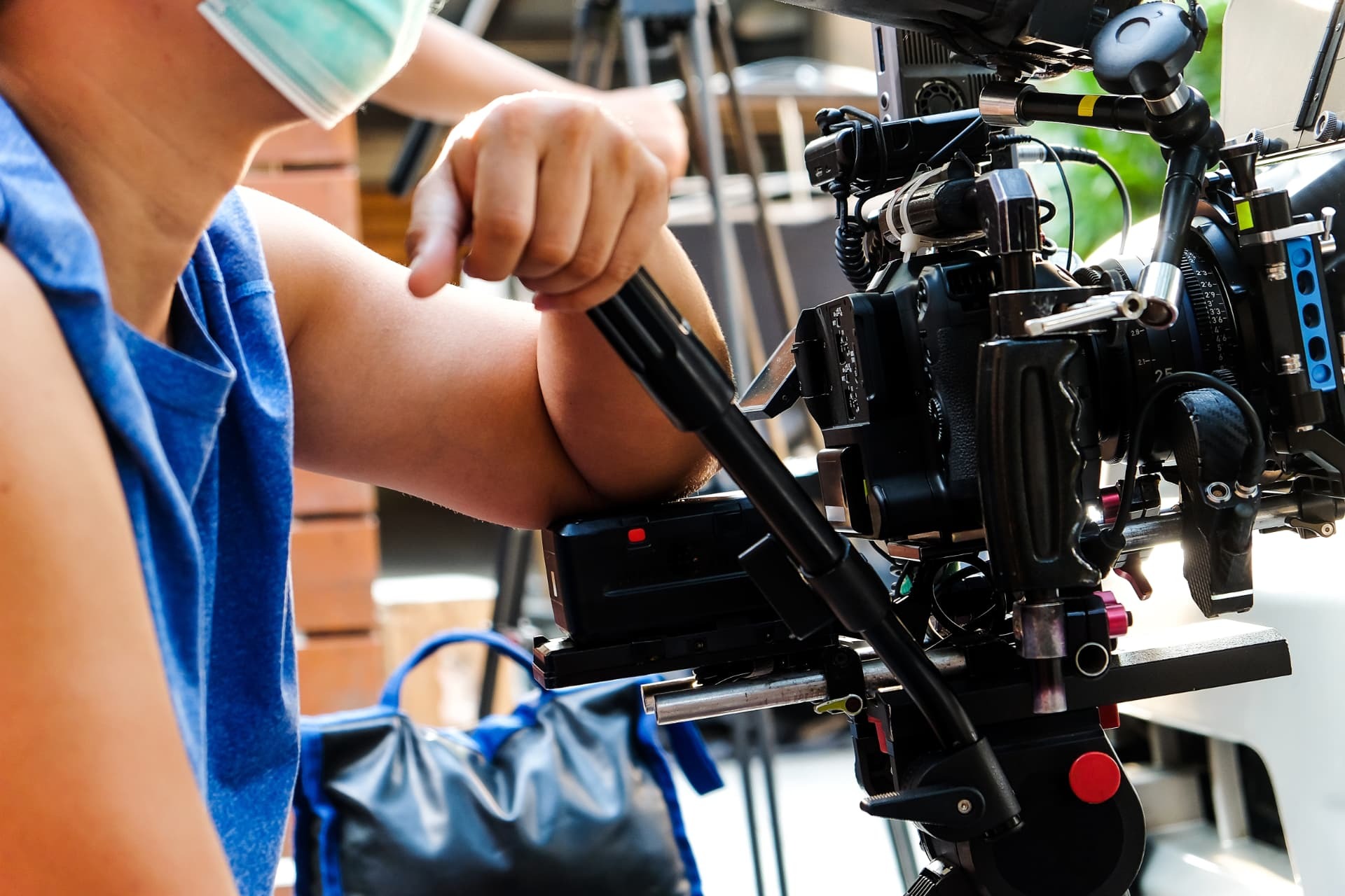 Crew member leaning on a cinema camera rig with a 25mm lens, ready for the next take.