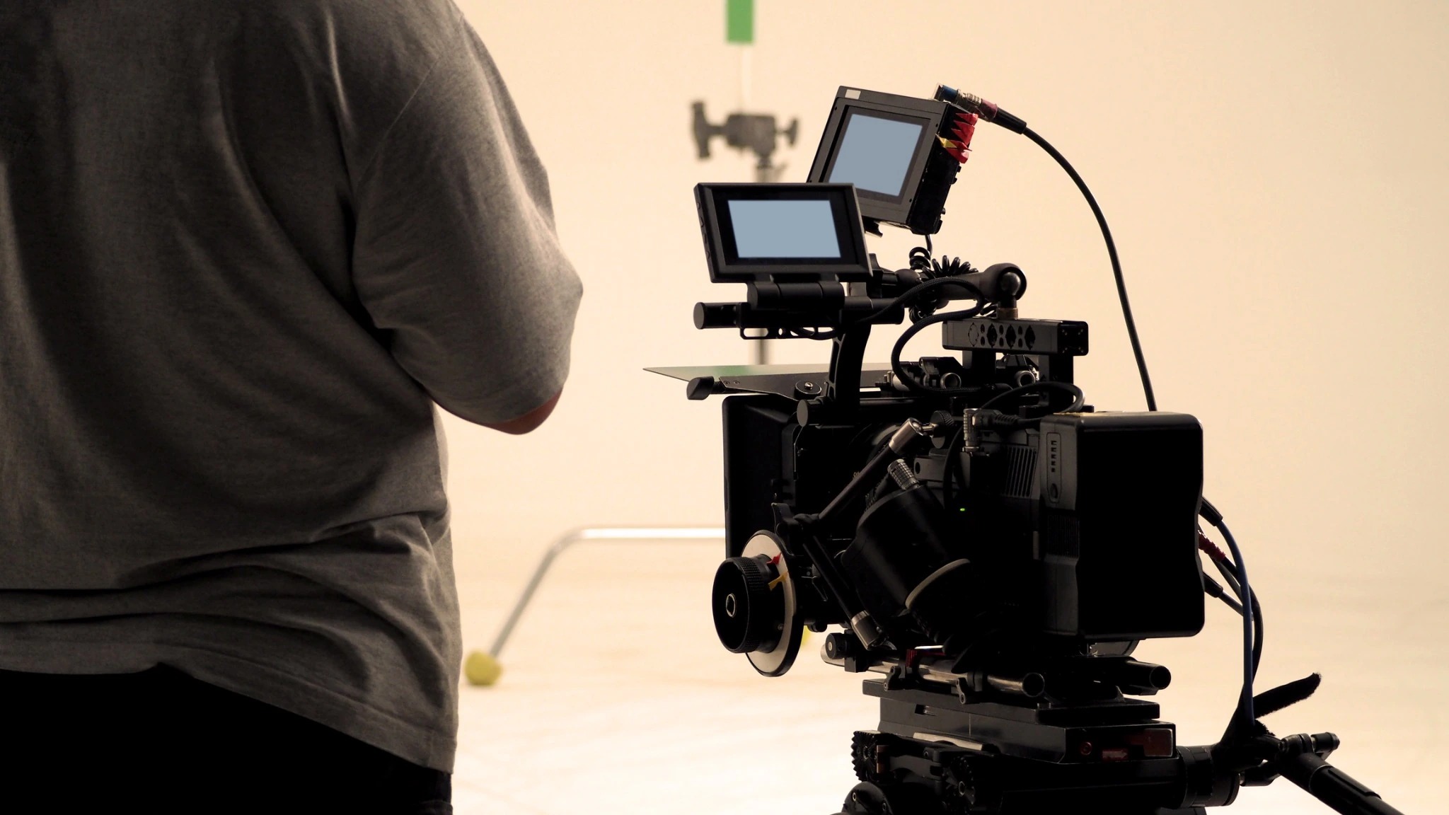 Rear view of a professional camera with two monitors beside a crew member.